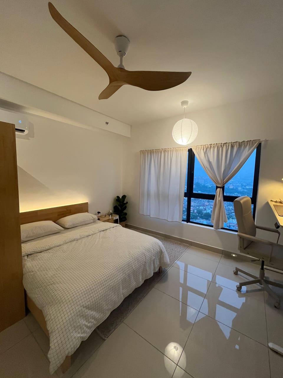 Sleeping area with ceiling fan, paper lantern and a city view at dusk