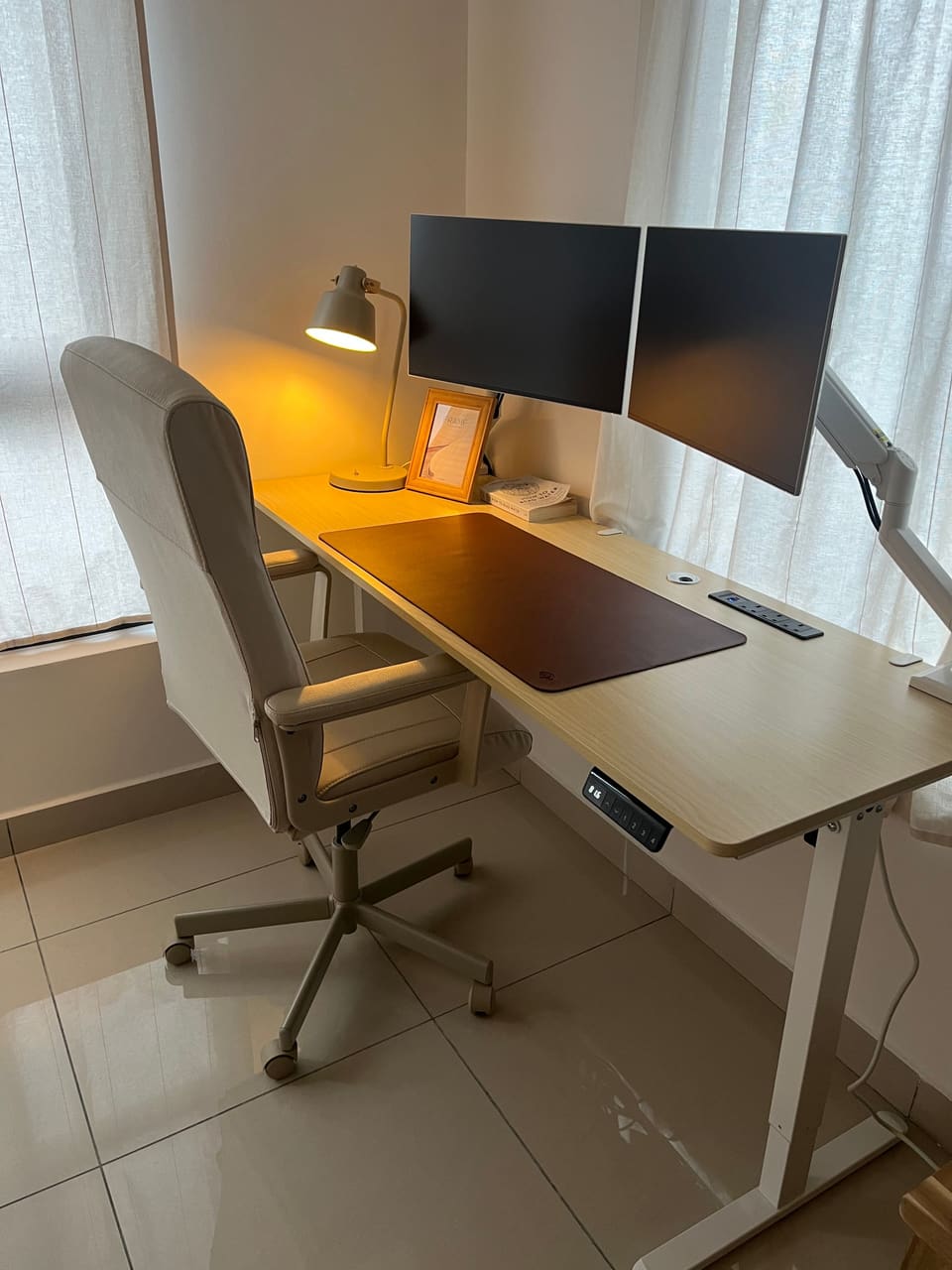 Electric standing desk with dual monitors, desk lamp and ergonomic chair